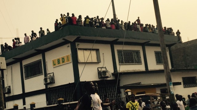 Crowds gather atop the LBDI bank building to watch the commotion. Photo: Sheik Jalloh.